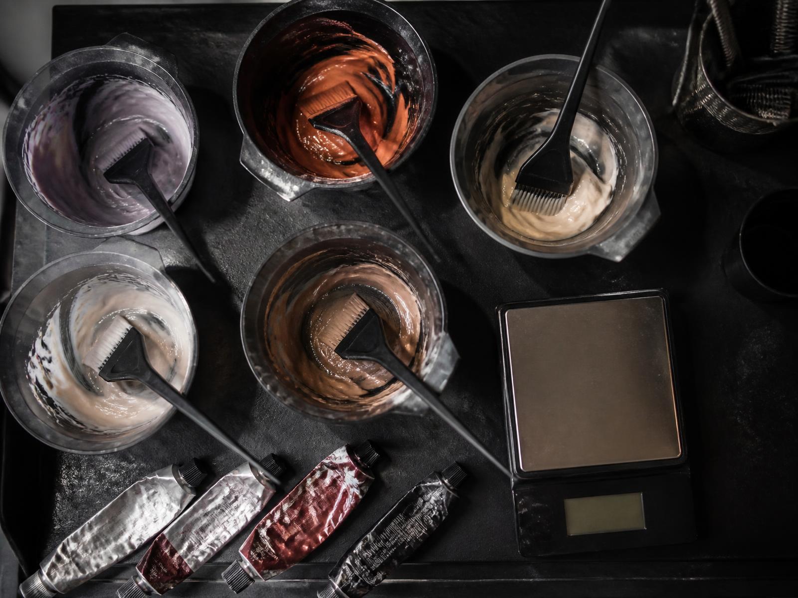 Overhead view of several tint bowls with leftover mixed colour, brushes and a scale
